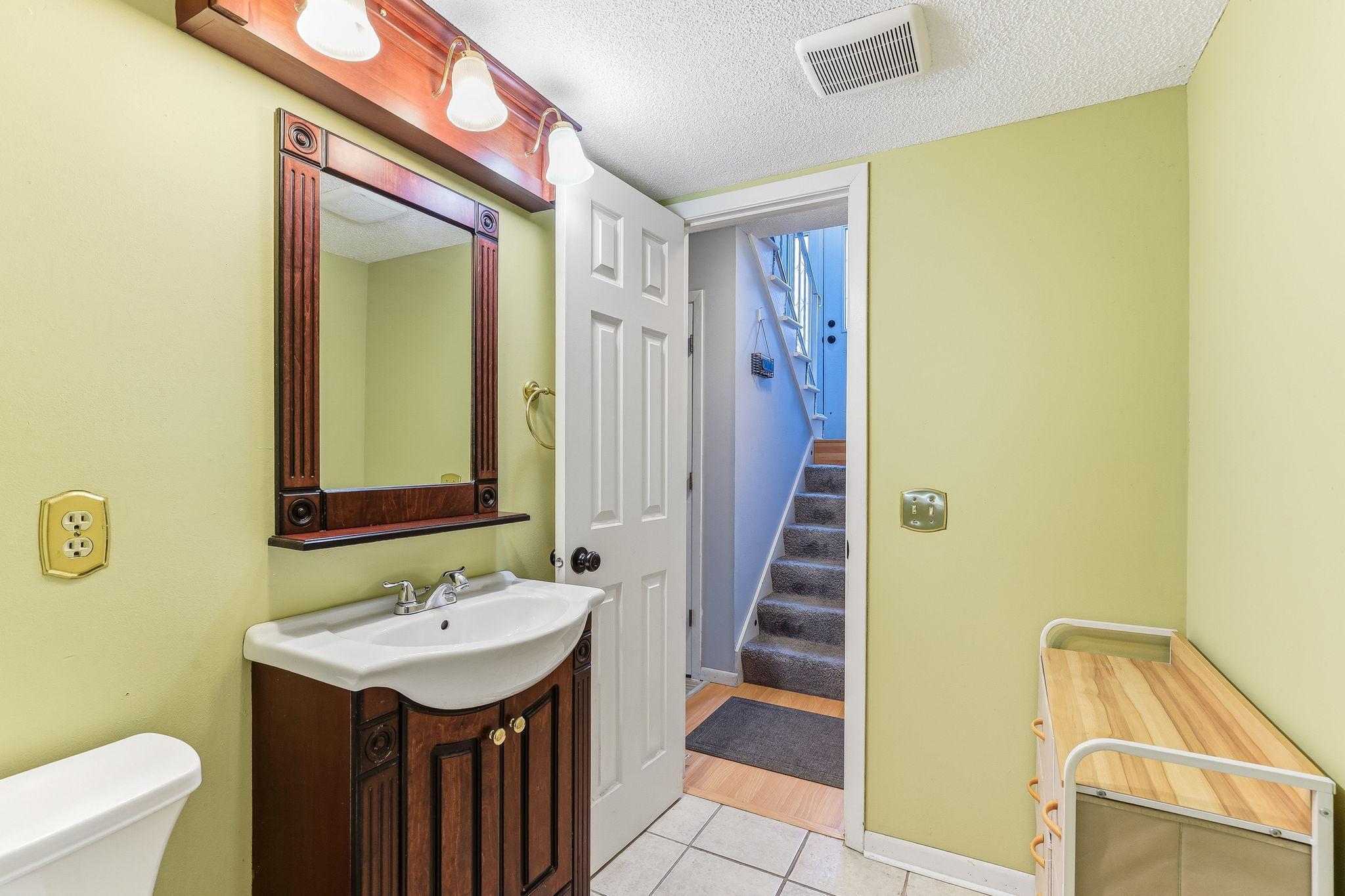 Bathroom with updated vanity, mirror, lighting, and a practical layout connected to the lower level.