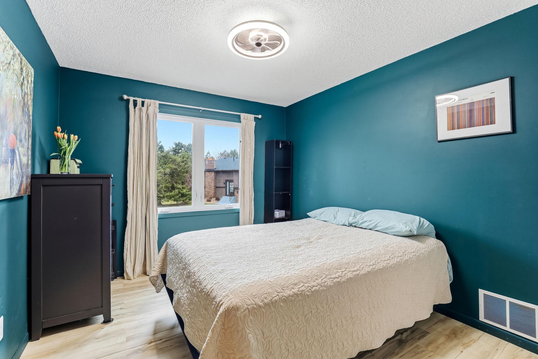 Comfortable bedroom with a large window that brings in natural light and offers views of surrounding greenery, creating a calm and inviting space.