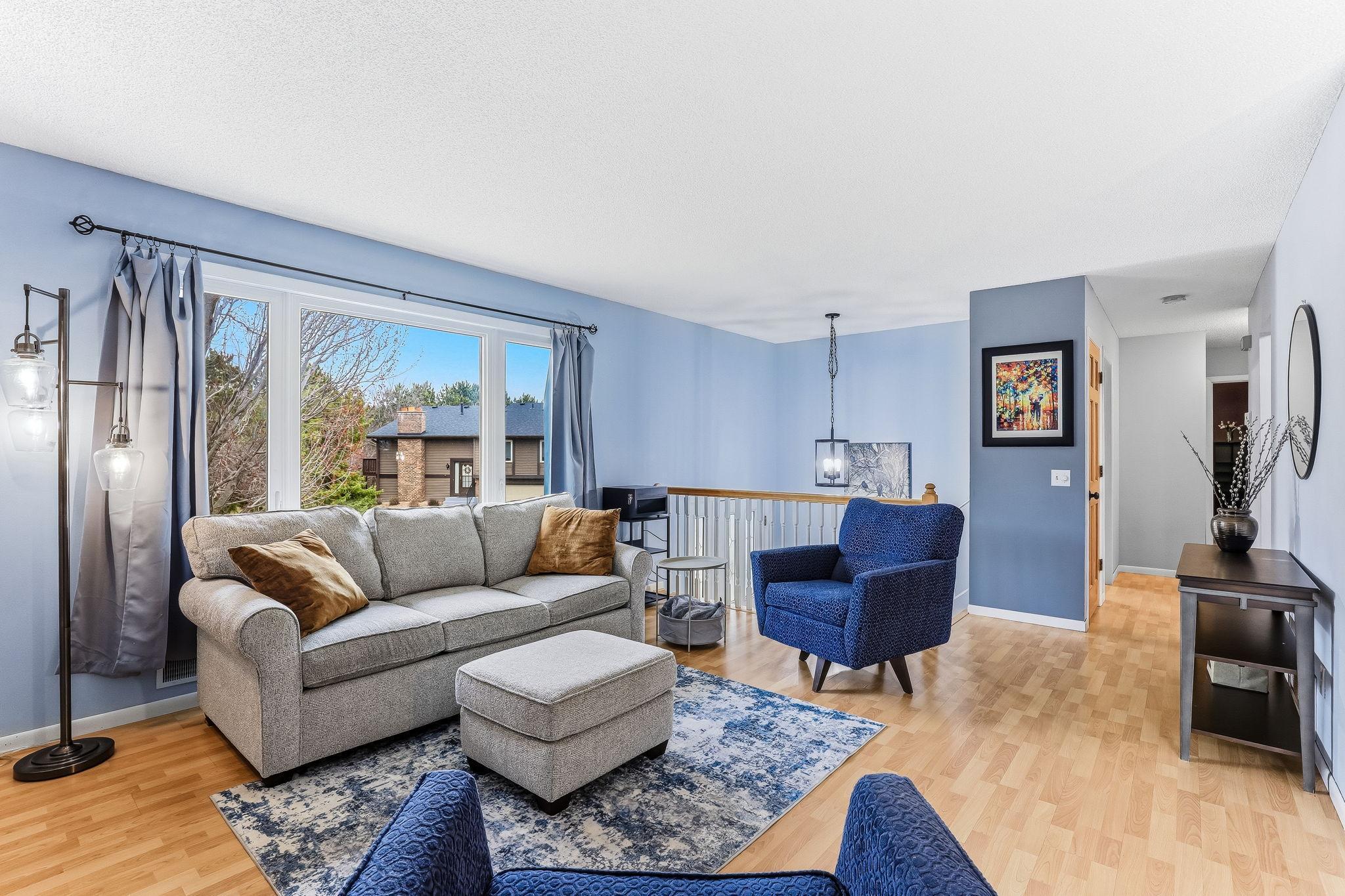 Bright main living area with large windows that bring in natural light and offer views of surrounding greenery, creating a comfortable and inviting space.