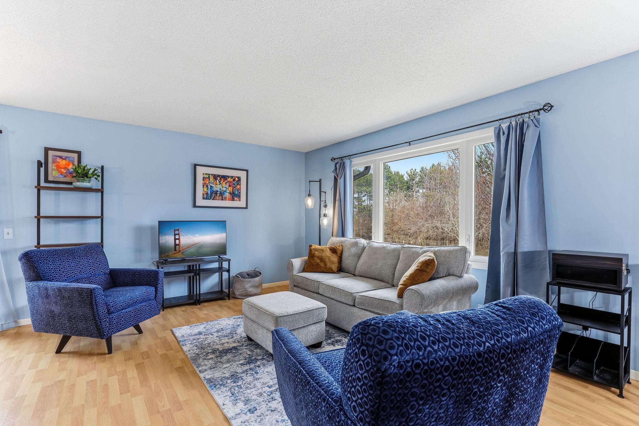 Light-filled living room with large windows overlooking natural surroundings, creating a comfortable and inviting main living space.