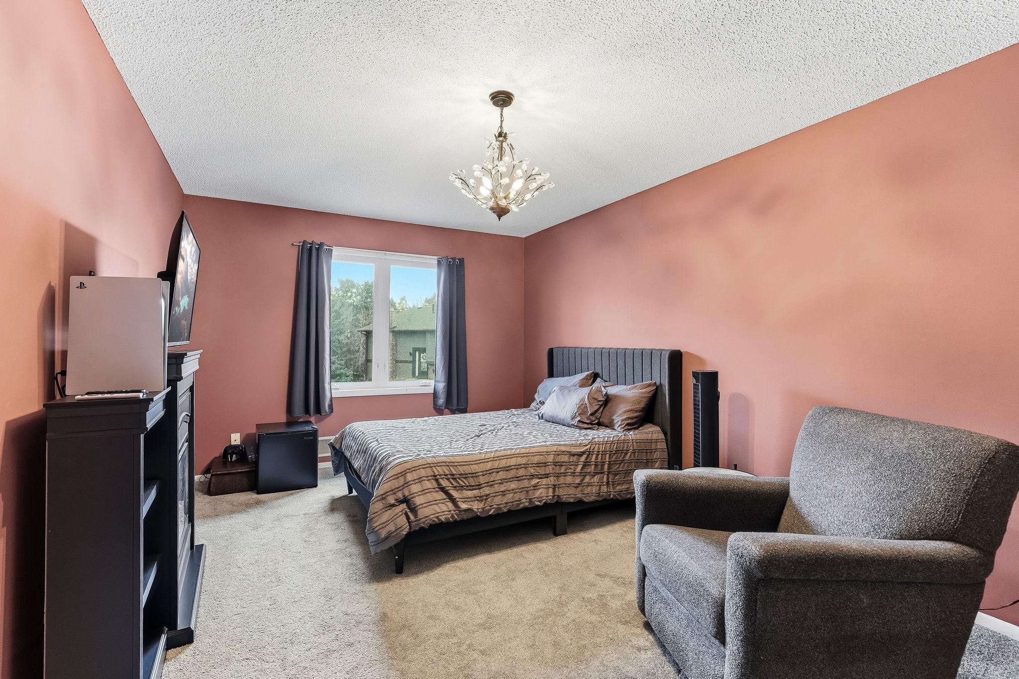 Spacious bedroom with large window, soft natural light, and flexible layout for sleeping, relaxing, or workspace use.