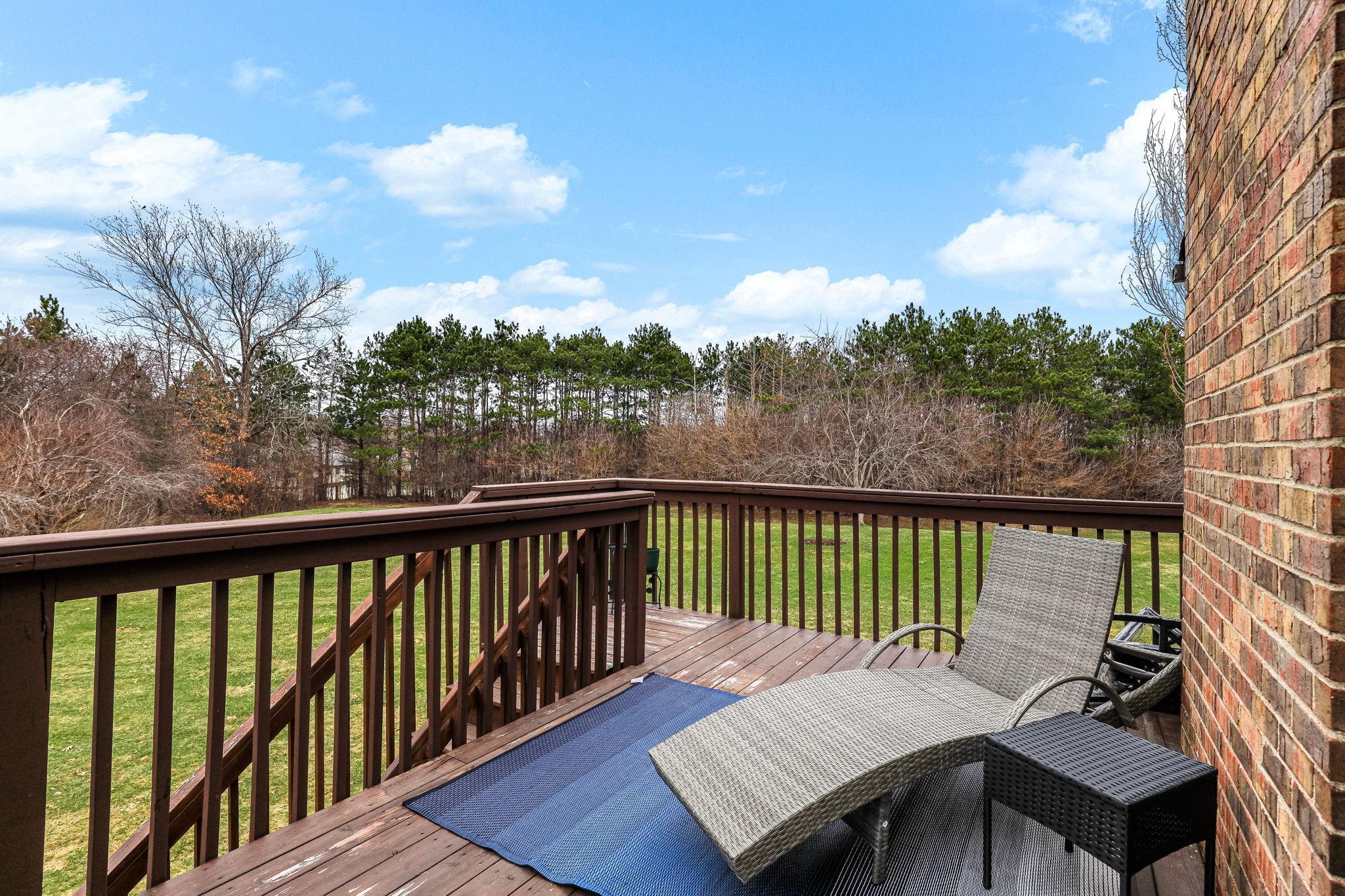 Elevated deck overlooking open green space and mature trees, creating a peaceful and private outdoor retreat.