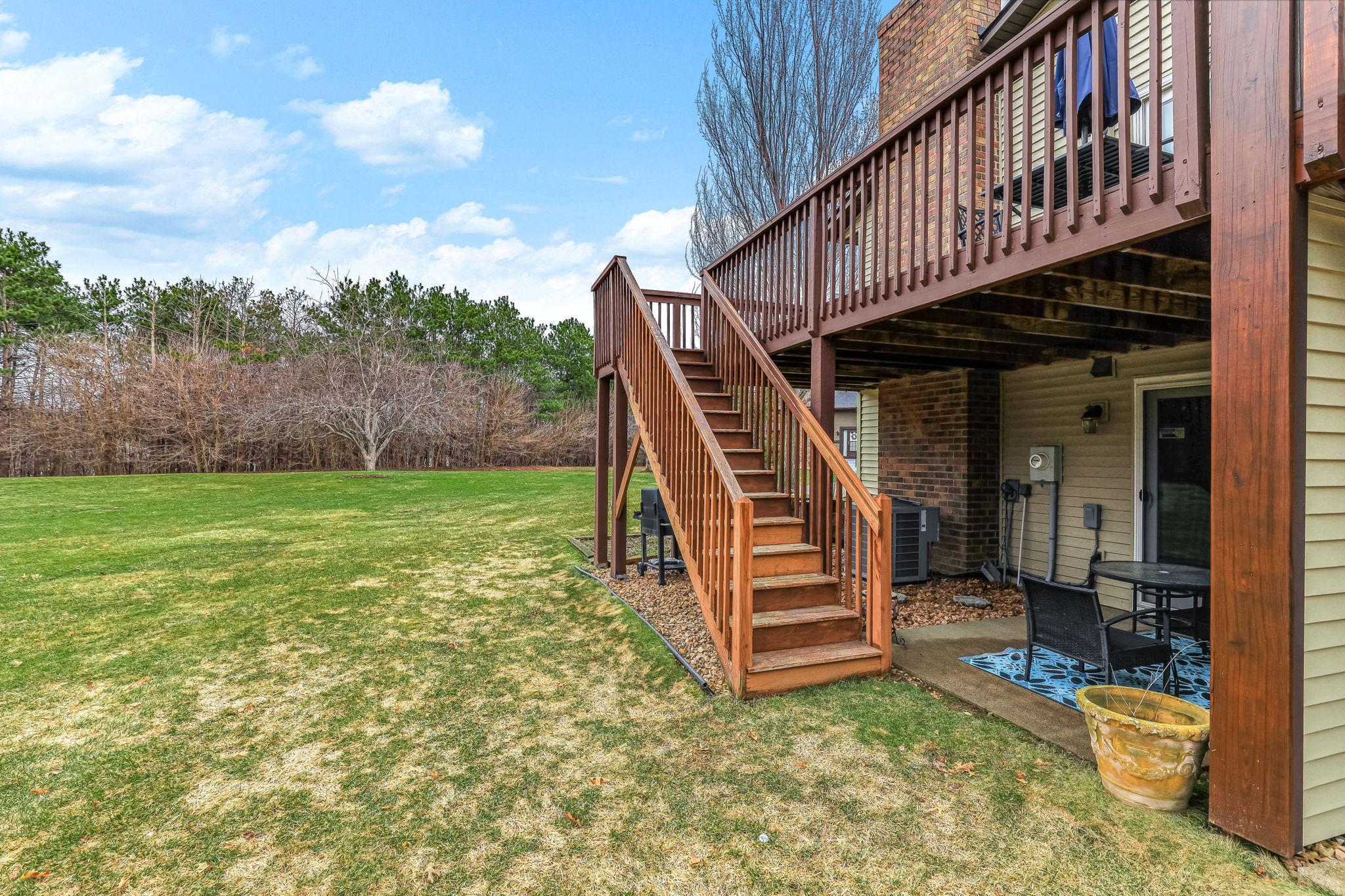 Rear exterior showcasing elevated deck, walkout lower level, and generous yard space.