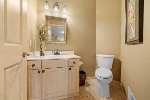 1/2 bathroom on the main level features maple vanity cabinet and ceramic tile flooring