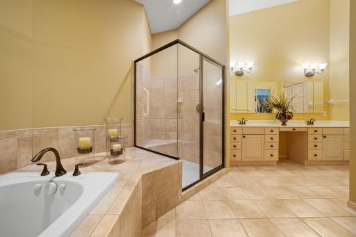 Oversized shower features ceramic tile surround, bench and glass enclosure