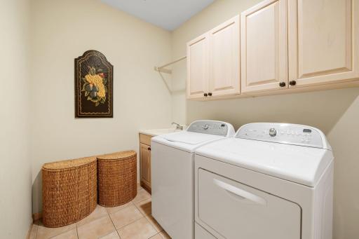 Laundry Room features maple cabinets that offers storage and a drop-in utility sink