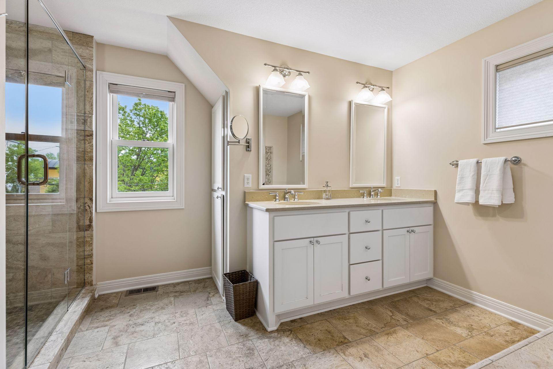 Dual sink vanity and ceramic tiled walk-in shower.