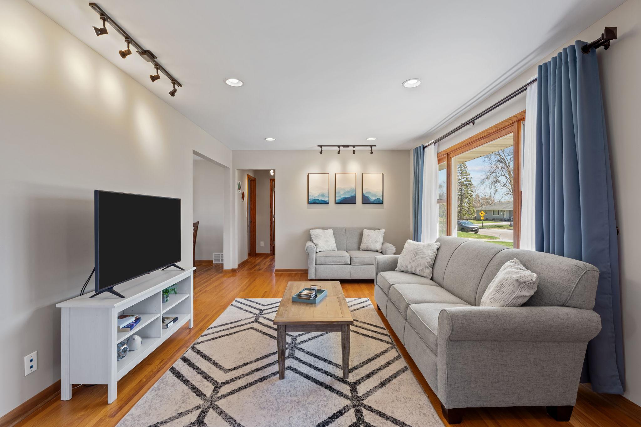 The nice-sized living room offers a comfortable layout highlighted by beautiful updated lighting, creating a warm and inviting space.