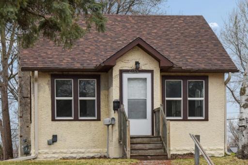 Charming front exterior with inviting entry, classic stucco finish,