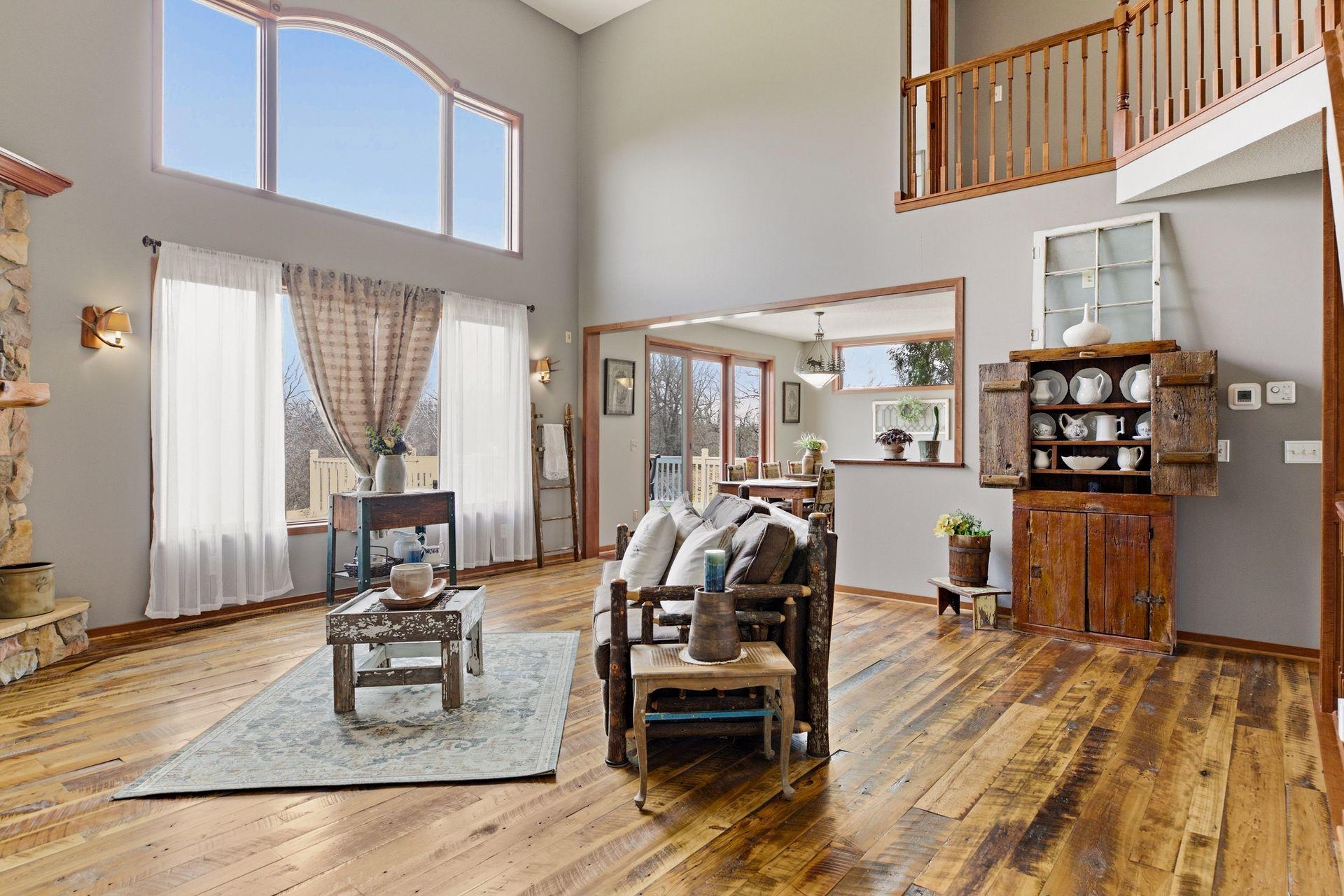 Two-story vaulted Great Room with reclaimed hardwood floors and a floor-to-ceiling stone gas fireplace.