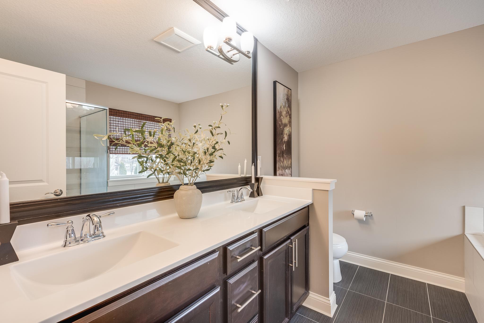 Onwer's bath with tile floors, soaking tub, tiled standalone shower, and dual sinks
