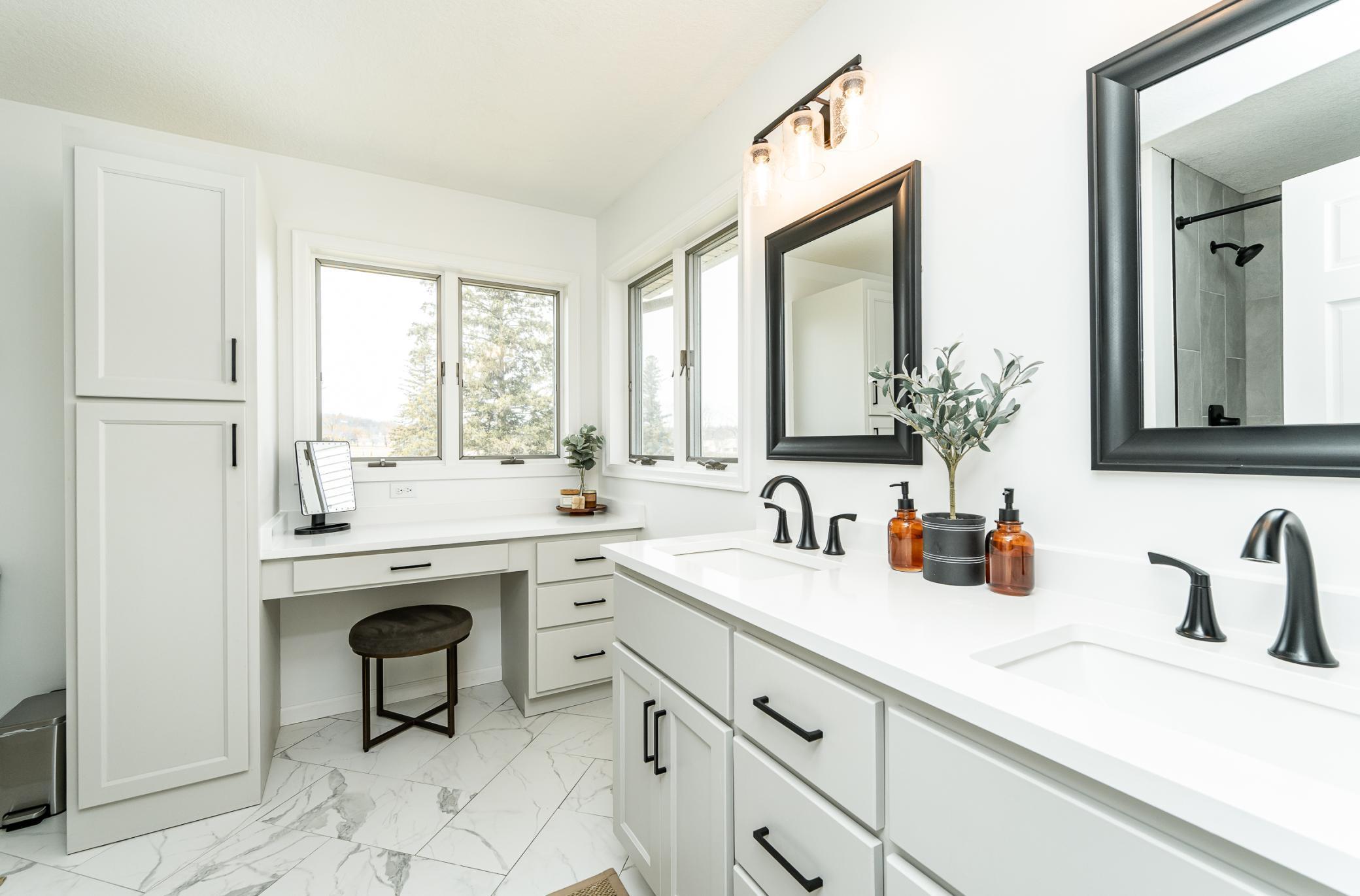 Beautifully updated primary bath featuring dual quartz vanity, beauty bar with natural light, beautiful tiled floors.