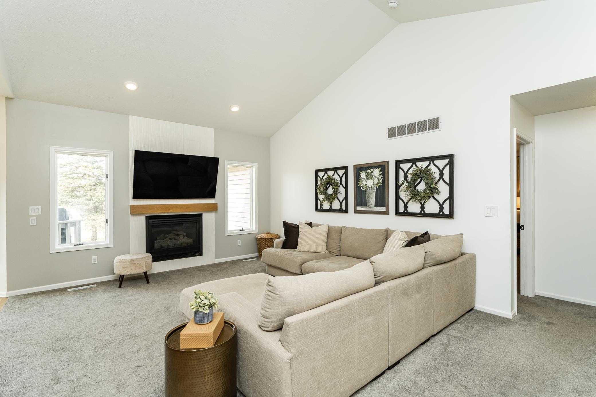Large living room accented with vaulted ceilings, custom tile fireplace surround and natural wood mantle.
