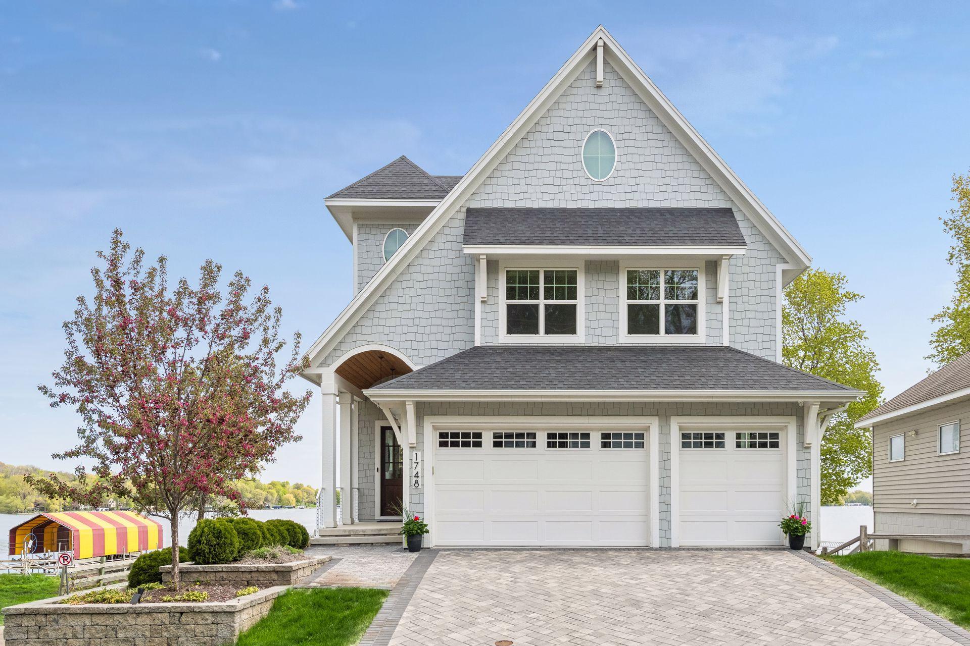 Welcome to 1748 Shorewood Lane, where a nautical aesthetic defines the entrance, featuring a graceful rounded covered entry and signature oval windows that hint at the luxury within.