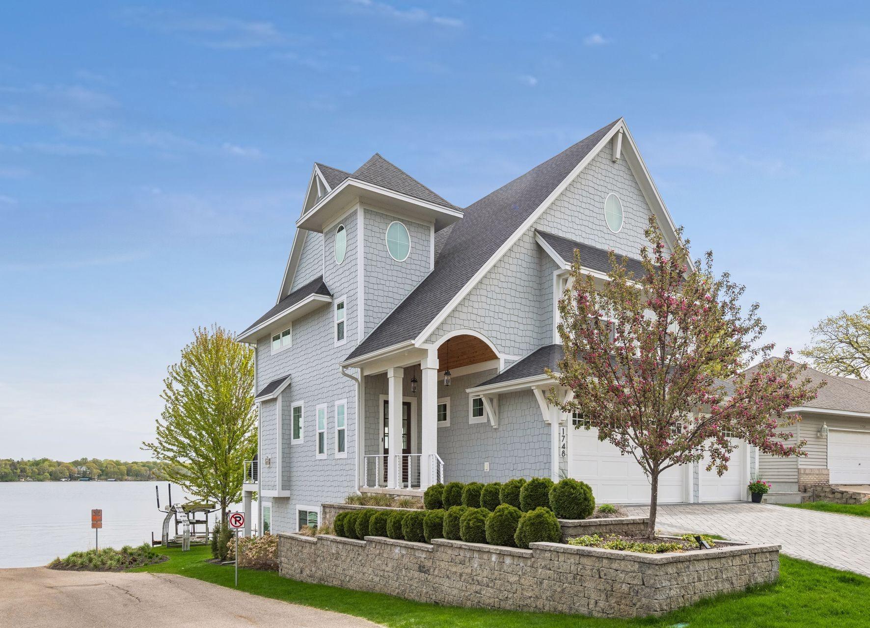 Sophisticated curb appeal meets durability with staggered shake siding, a 2022 roof, and a custom herringbone paver driveway framed by professional landscaping.