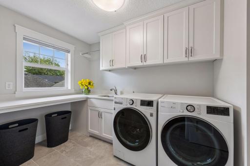 Convenient second-floor laundry room with sink and storage just off the primary closet.