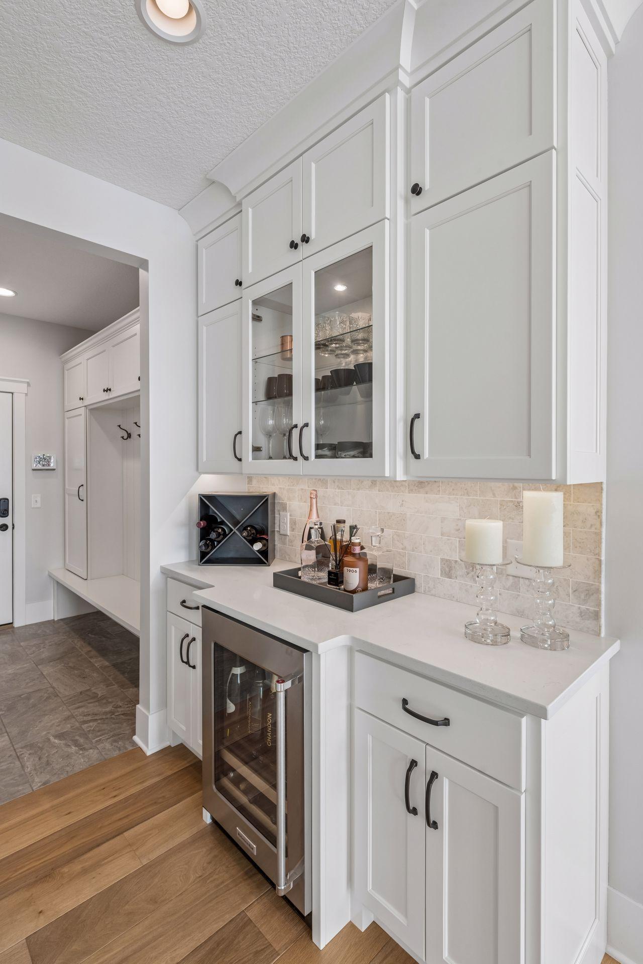Elevate your hosting with this main-level beverage station with elegant glass cabinets and chilled beverage center.