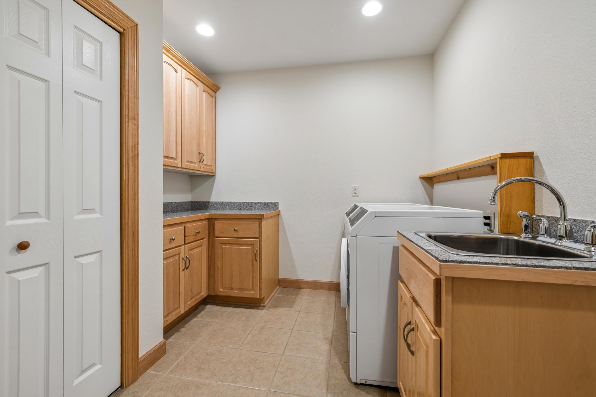 Generously sized laundry room adds exceptional functionality with built-in cabinetry, sink, and counter space for organization
