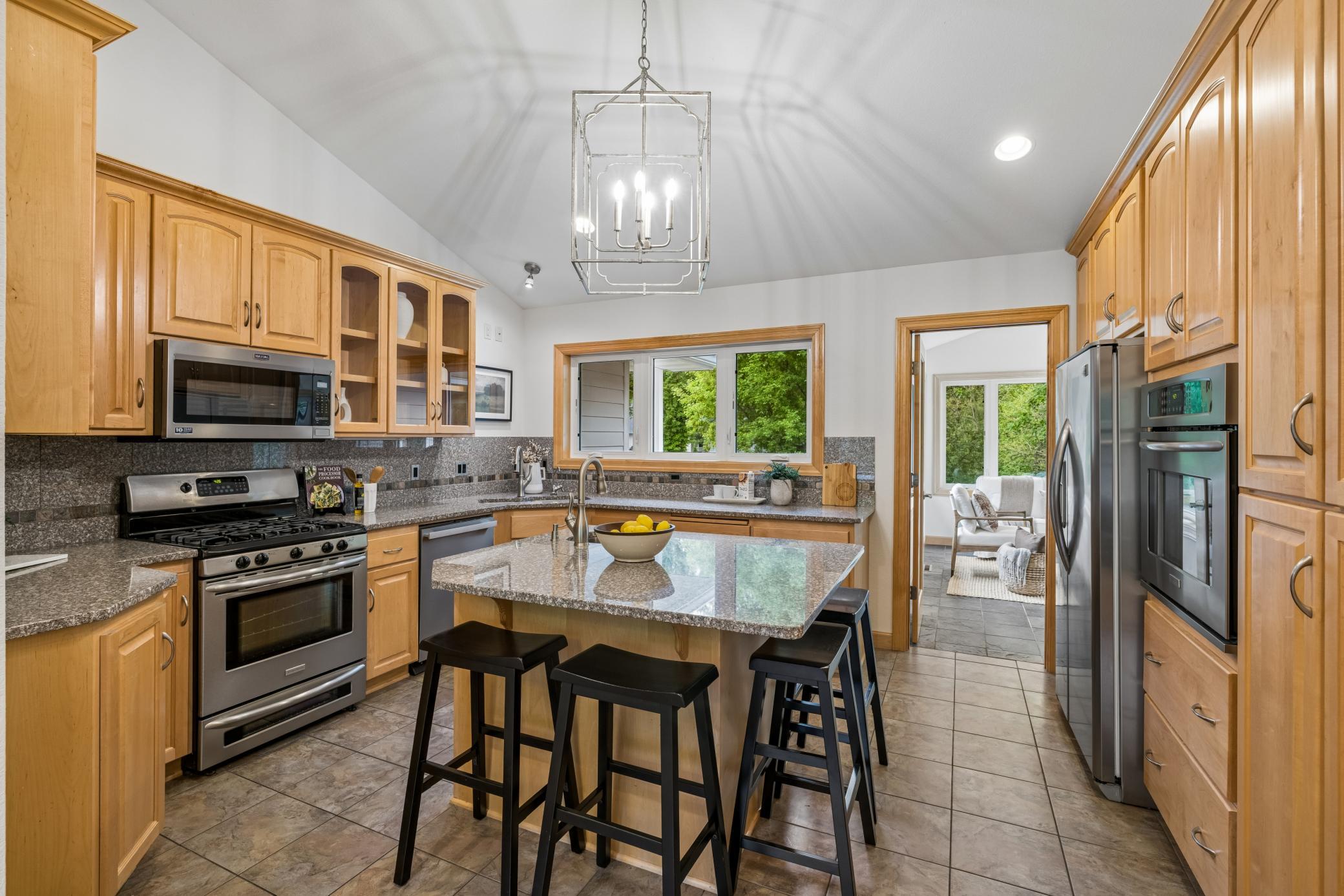 Granite countertops, stainless steel appliances, and a center island with a prep sink create a functional and stylish workspace.