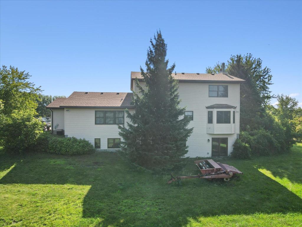 Rear elevation showcasing the expansive yard, walkout lower-level access, and private tree-lined backdrop.