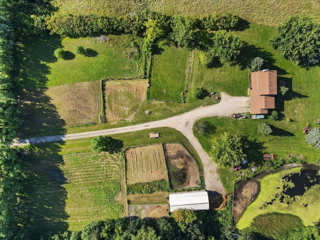 Aerial overview highlighting the layout of the property, fenced pasture areas, barn, pond, and scenic countryside surroundings.