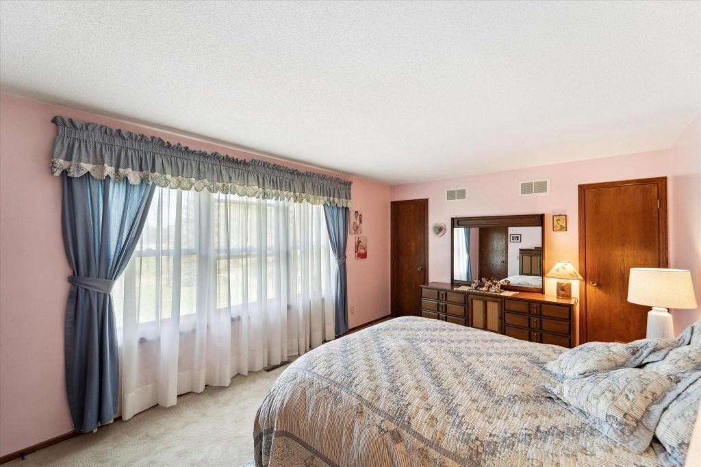 Comfortable primary suite offering large windows, peaceful views, and generous closet space.