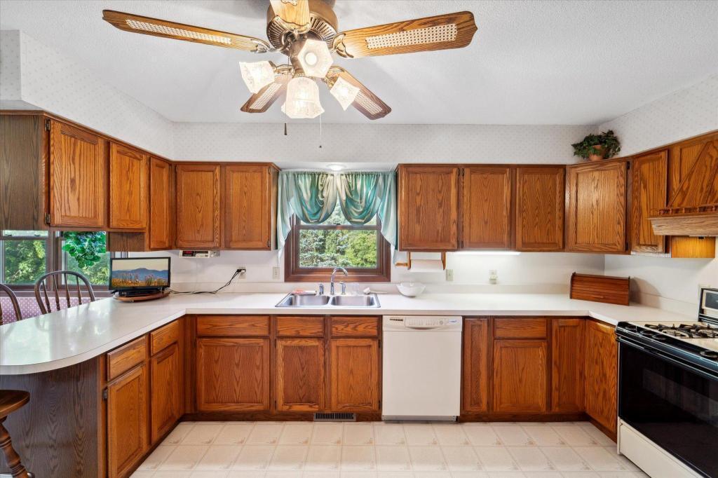 Spacious kitchen featuring abundant oak cabinetry, generous counter space, and a window overlooking the peaceful backyard setting.
