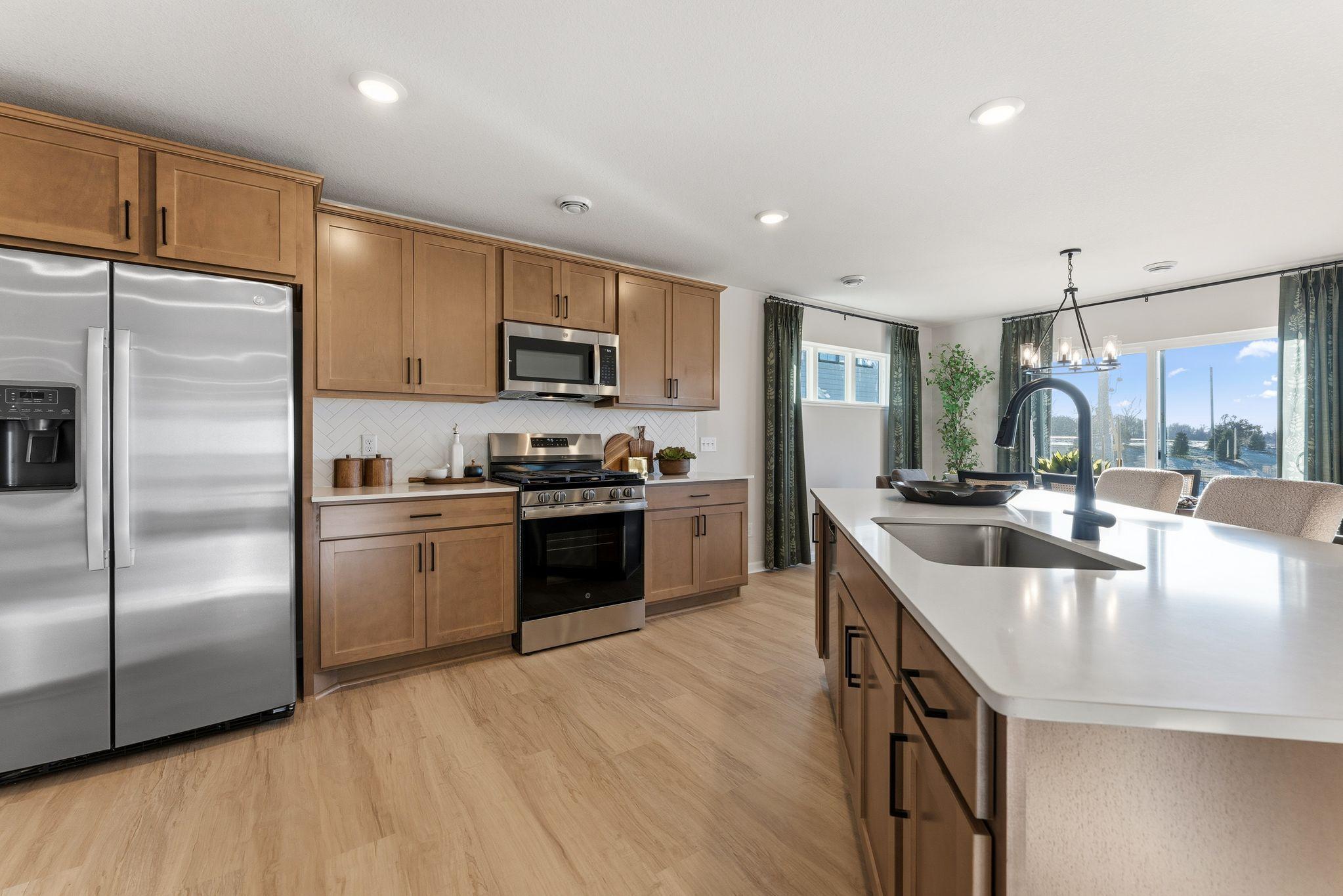 Welcome home to your Concord C Floorplan by M/I Homes! Soft close doors & drawers, SS appliances: gas range & microhood that vents to exterior, stylish LVP flooring & stone tops. Photo for reference only. Style, color and collections will vary.