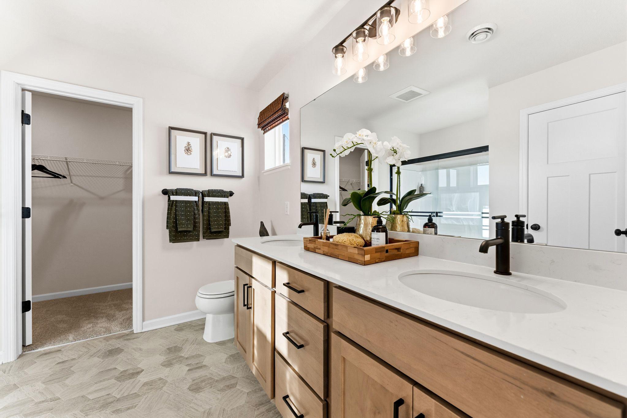 Private Primary Suite Bath offers raised vanity, stone tops, stylish flooring and spacious walk-in closet! Photo for reference only. Style, color and collections will vary.