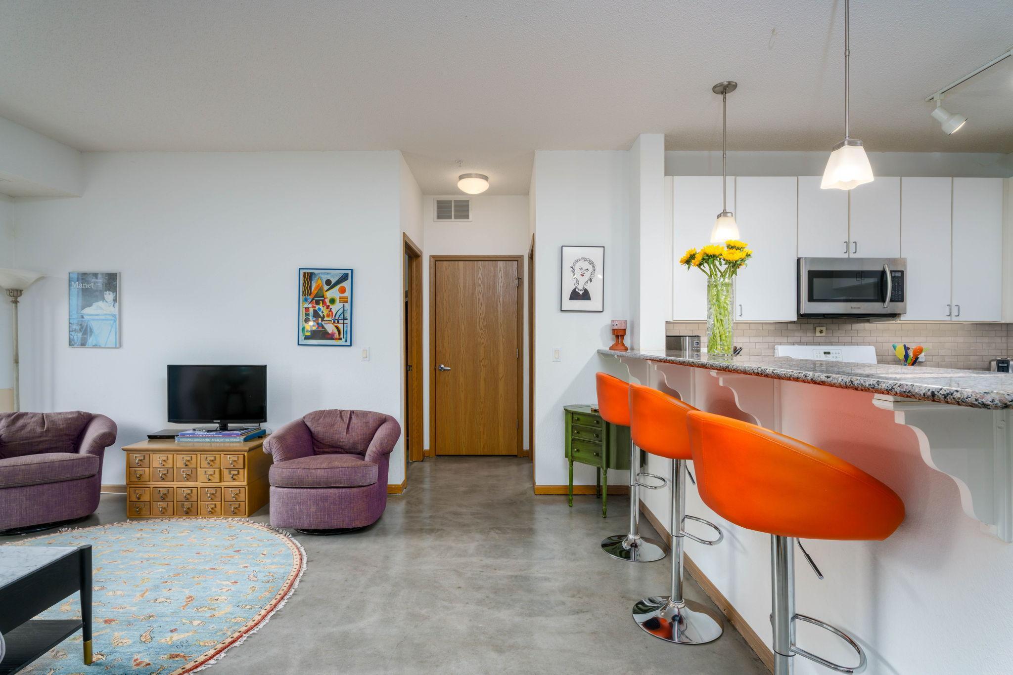 Open and roomy floor plan - view towards primary bedroom, bathroom, and laundry closet. Note the refinished concrete floors throughout for a modern feel.
