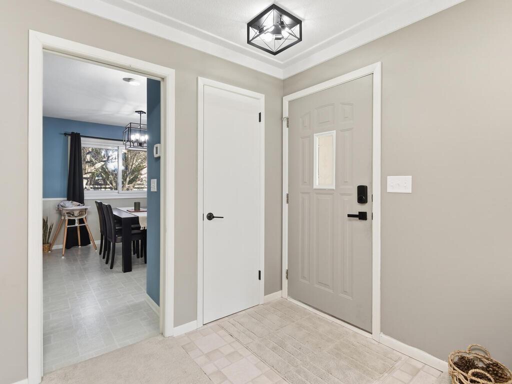 The functional entry area features durable flooring and updated lighting, offering a glimpse into the formal dining room.