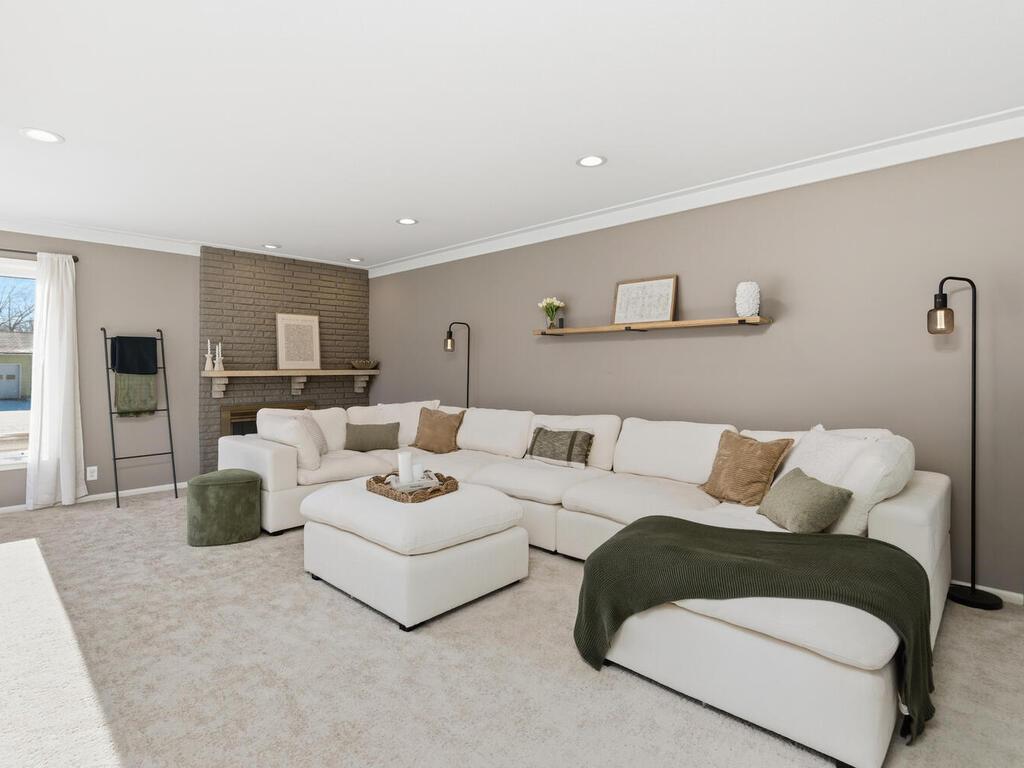 The light-filled living room features fresh neutral paint, plush new carpeting, and a cozy fireplace with a contemporary mantel.