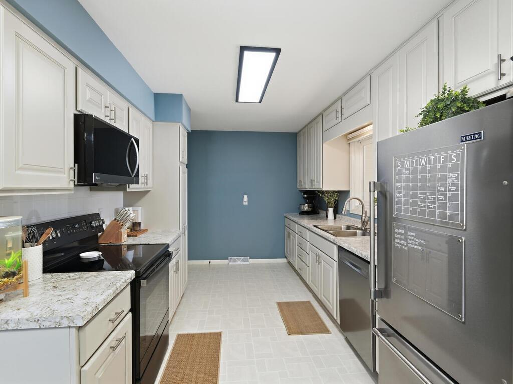 Prepare meals in this thoroughly updated kitchen, complete with light gray cabinetry, modern hardware, and sleek black appliances.