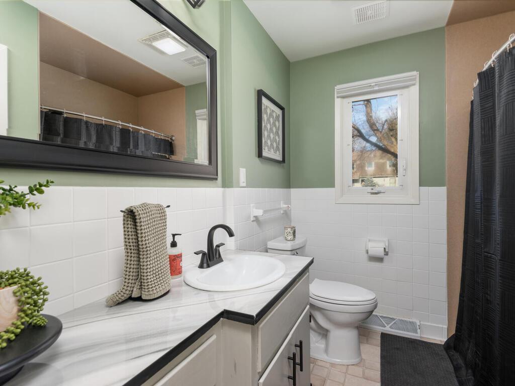 Completely remodeled bathroom highlights a modern vanity with integrated sink, updated mirror, and contemporary lighting.