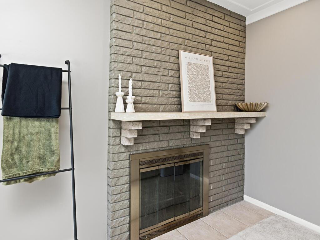 The brick-surround fireplace serves as a beautiful focal point, updated with a clean, neutral finish.