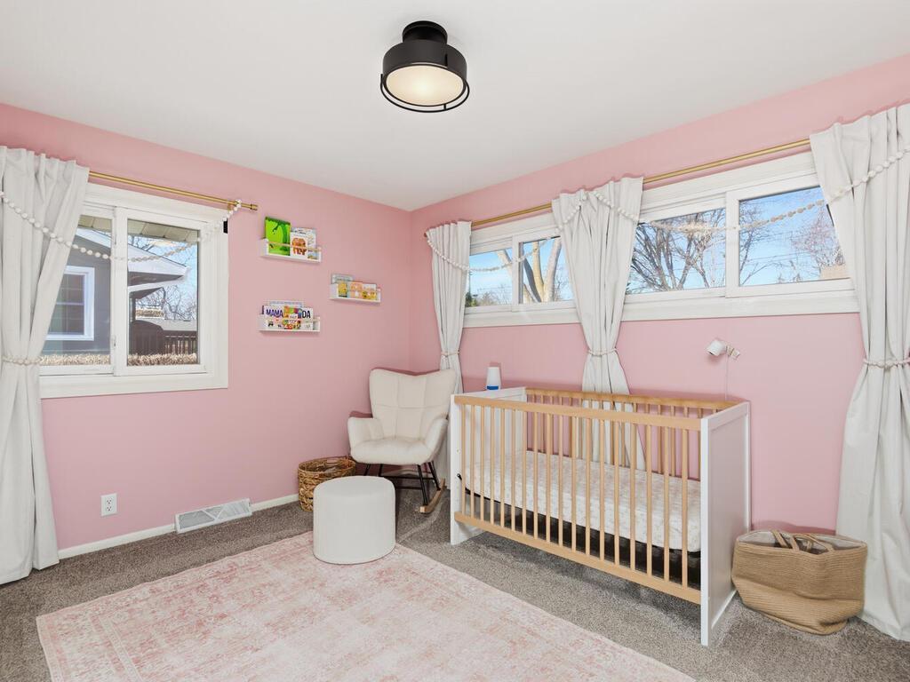 This delightful second main-level bedroom boasts soft pink paint, fresh neutral carpet, and wide windows.