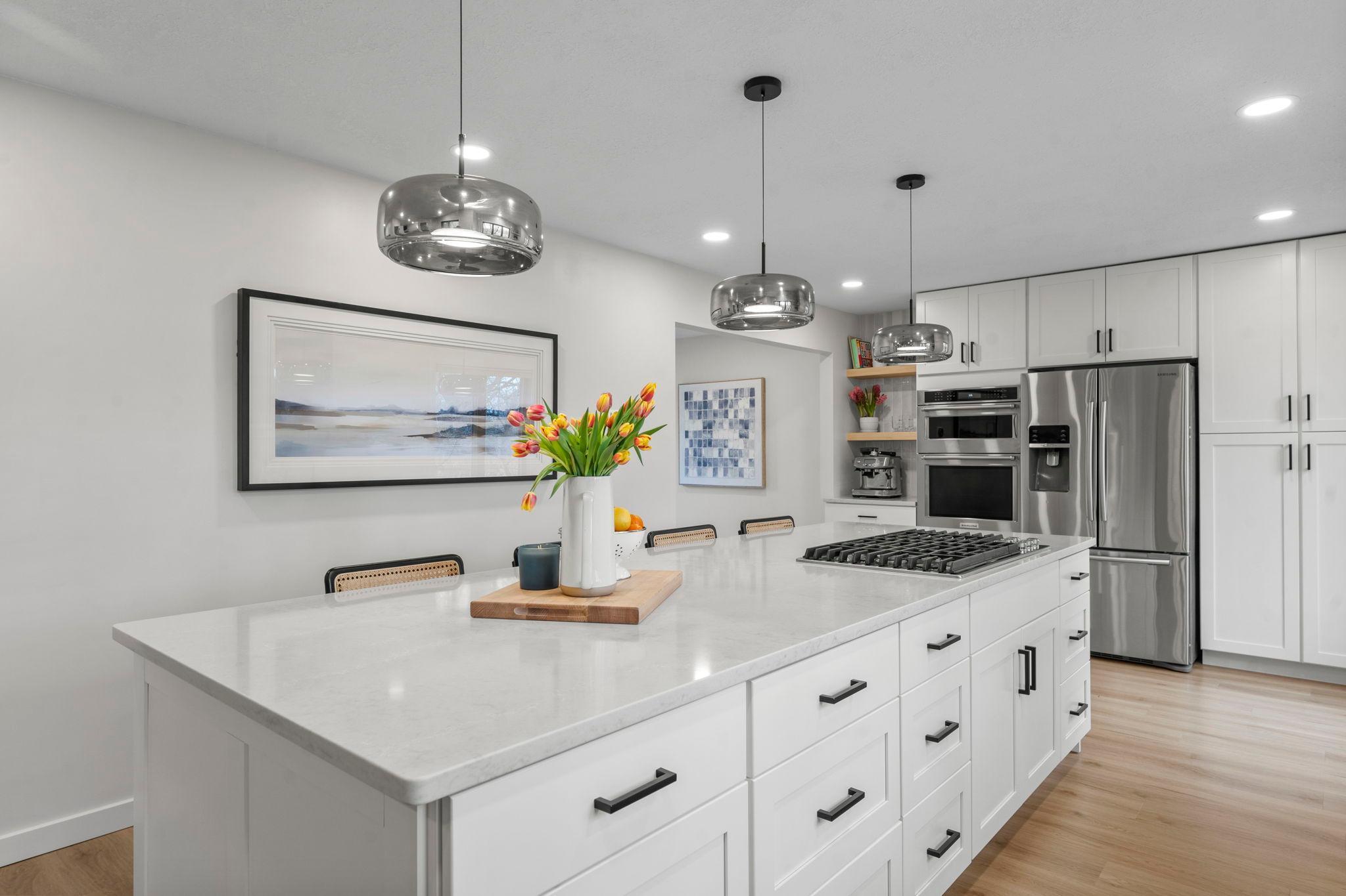 Highlights include a gas cooktop, modern pendant lighting, stainless steel appliances, and a stylish tile backsplash.