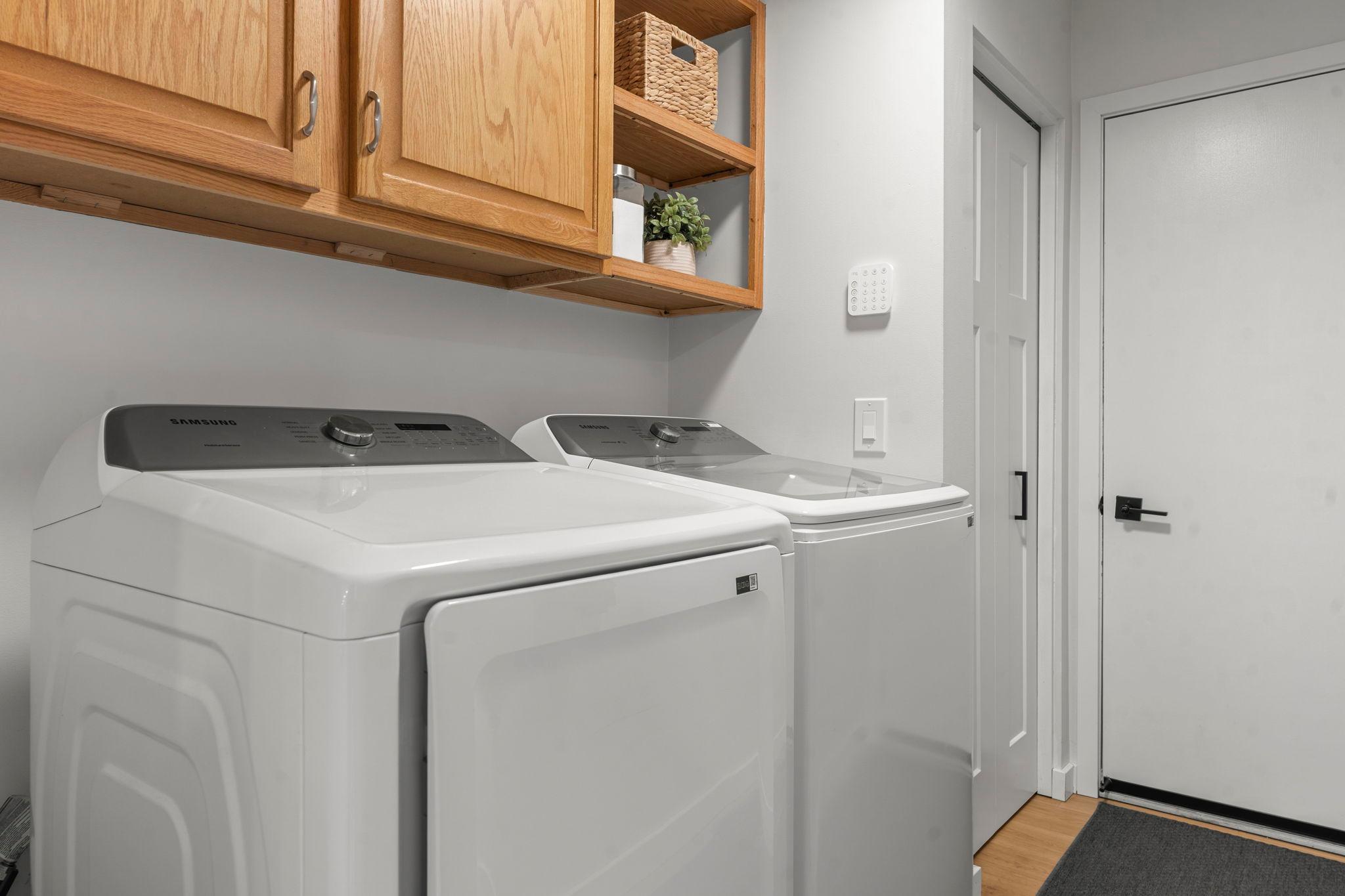 The main level also includes a convenient laundry room with Samsung washer and dryer, overhead cabinetry, a storage closet, and access to the attached two-car garage.