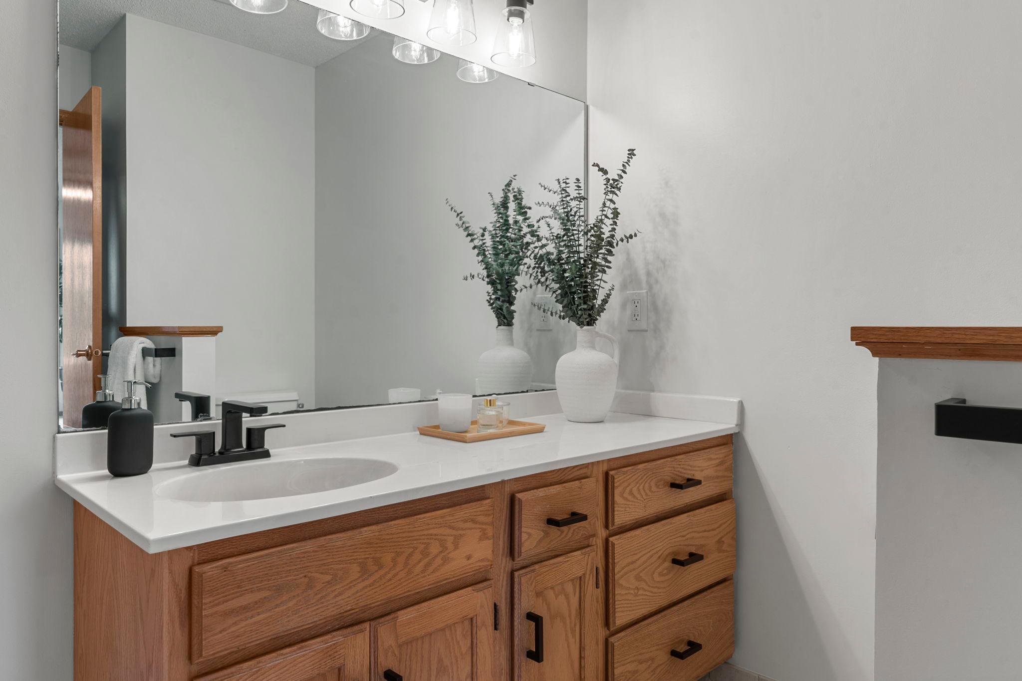 The private ensuite bath features tile floors, a soaking tub, walk-in shower, and single vanity with ample storage.