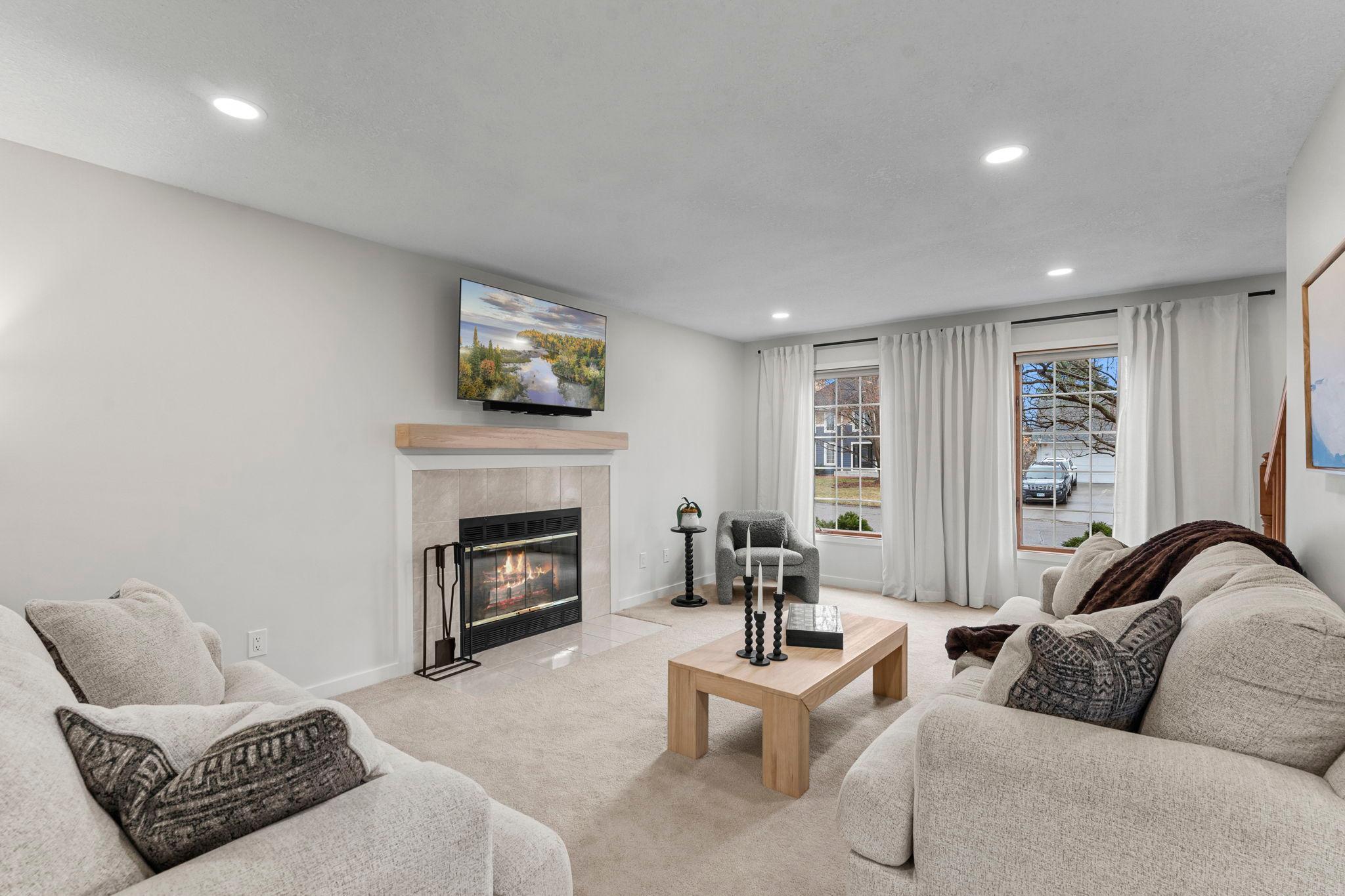 The main level living room offers carpeting, recessed lighting, front-facing windows, and a cozy gas fireplace with tile surround and mantel.
