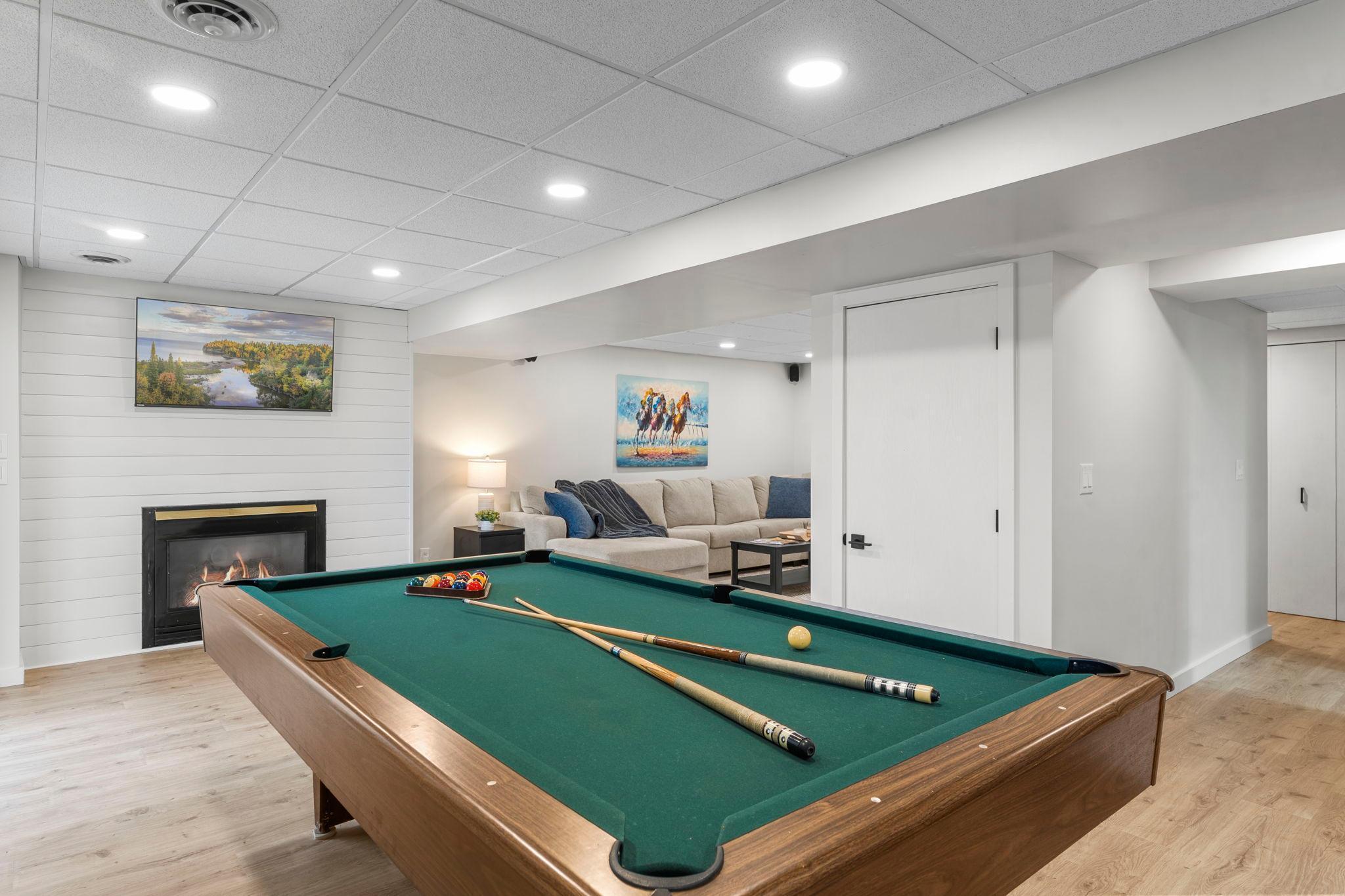 The recreation area offers a gas fireplace accented by an updated shiplap surround and walkout access to the backyard patio.