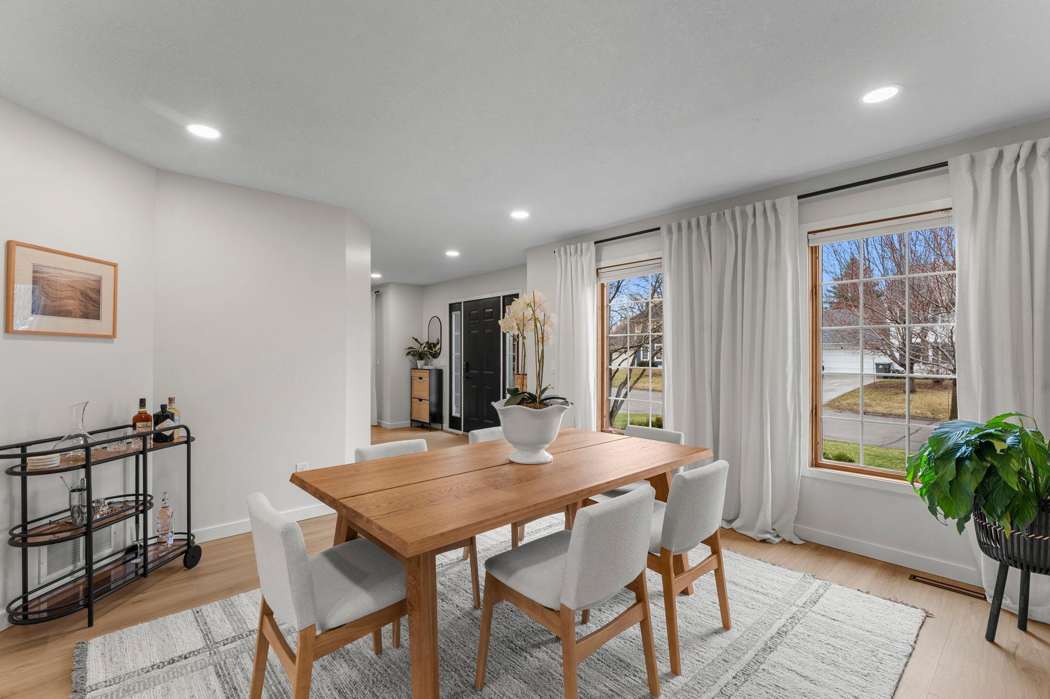 The formal dining room, located just off the other side of the kitchen, features luxury plank flooring, recessed lighting, and a large front-facing window that fills the space with natural light.