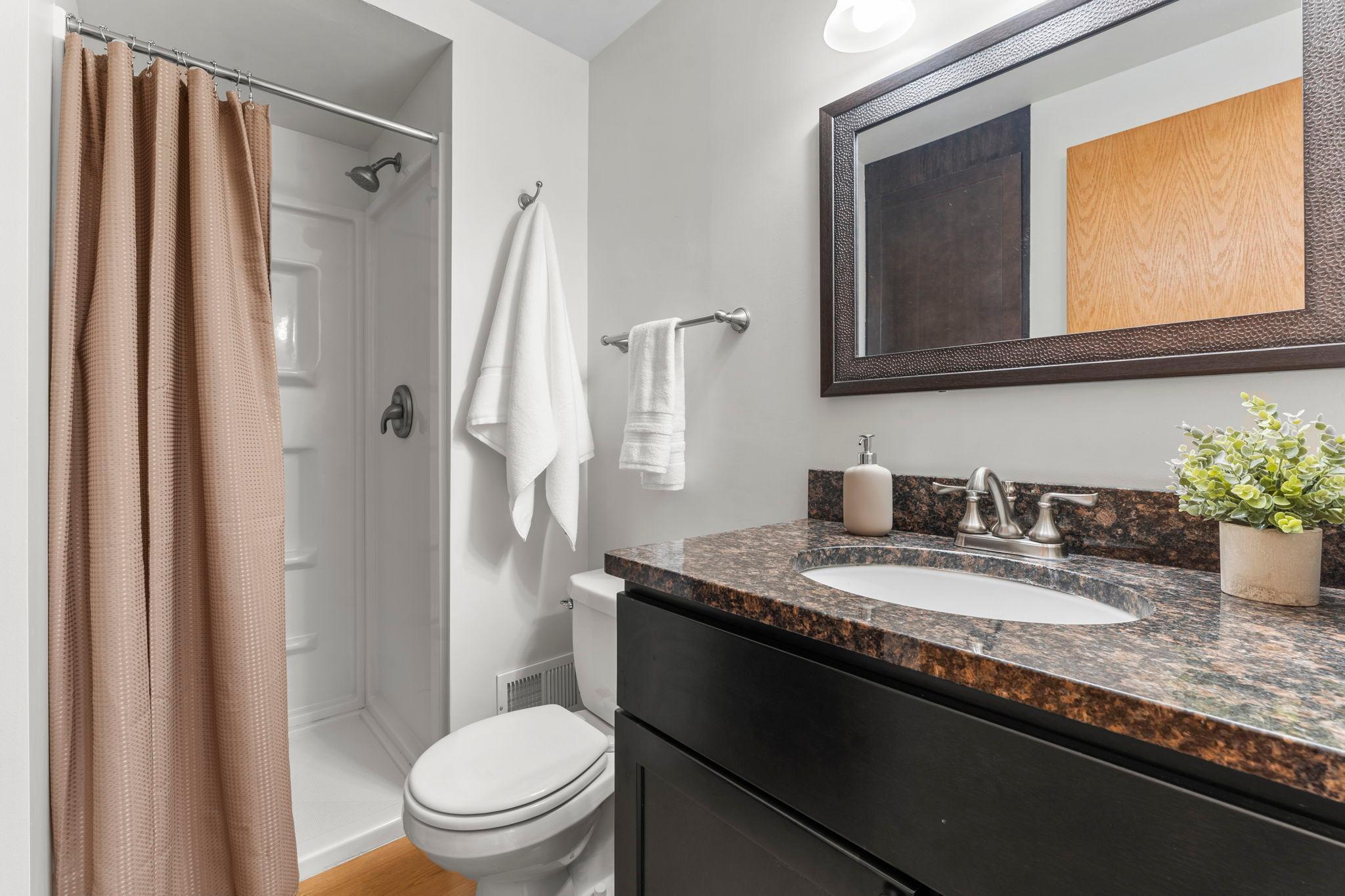 The nearby ¾ bathroom features a walk-in shower and granite-topped vanity.