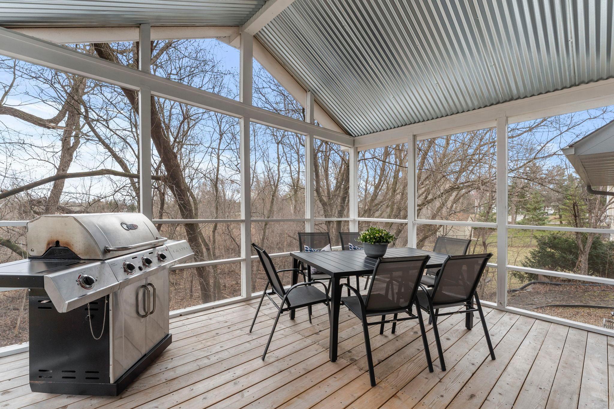 The informal dining area flows seamlessly from the kitchen and provides access to a spacious screened and covered deck—perfect for indoor-outdoor gatherings while enjoying peaceful wooded views and a pond backdrop.