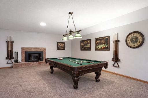 Generously sized lower-level family room with a cozy fireplace. Virtually stage image.