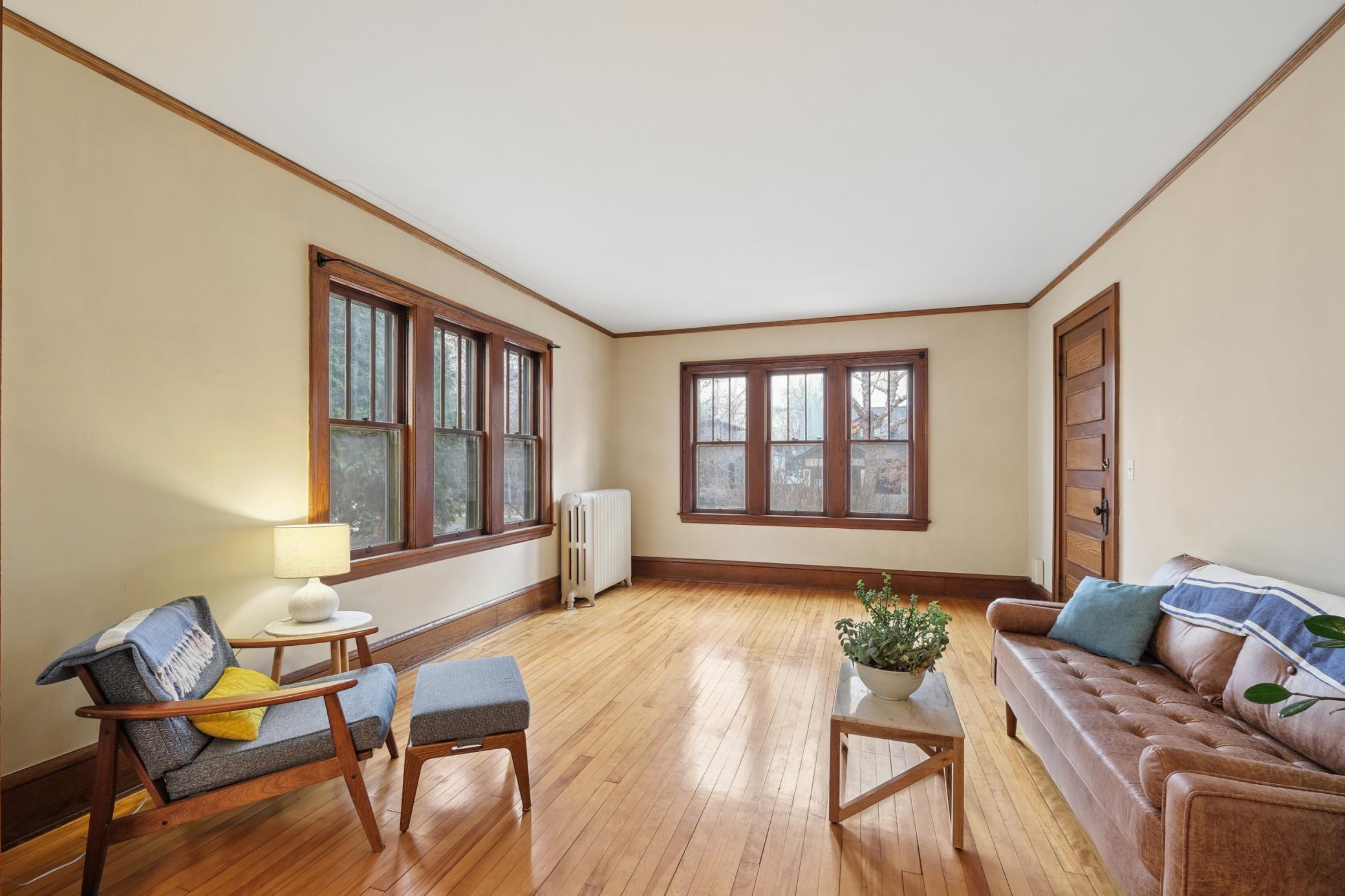View of unit 2's living room featuring original hardwood floors, woodwork, and lots of natural sunlight.