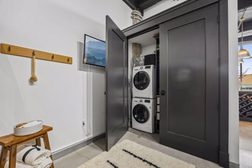 A custom cabinet with French doors in this space conceals a washer and dryer with added storage, blending utility with elegance.