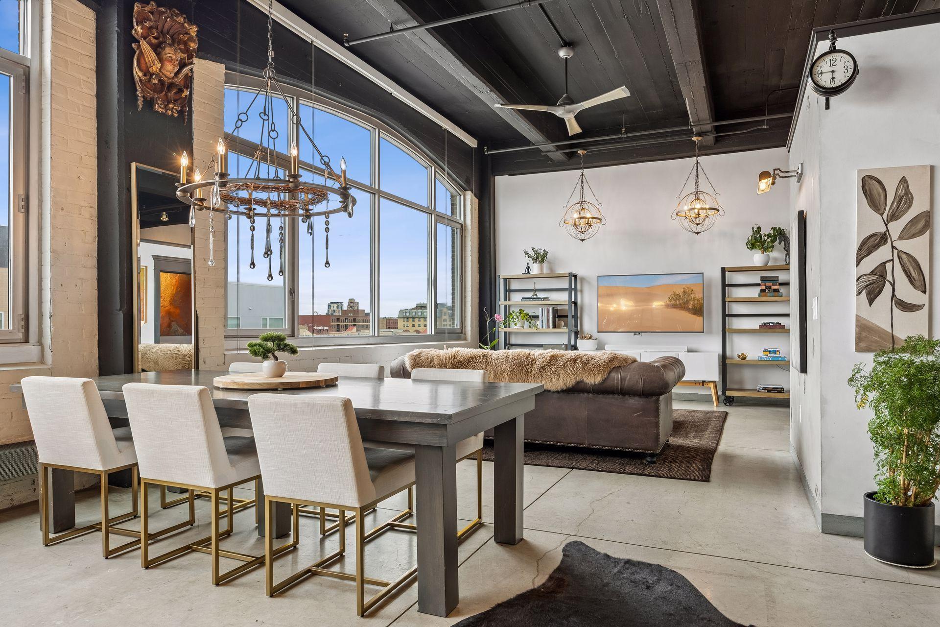 From the kitchen, the living and dining areas unfold toward a striking media wall, with a dramatic expanse of arched windows drawing in natural light from the left.