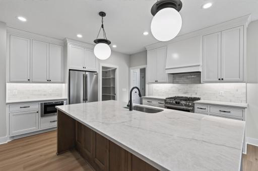 A chef's dream kitchen featuring a massive quartz island, premium appliances, walk-in pantry, and custom cabinetry.