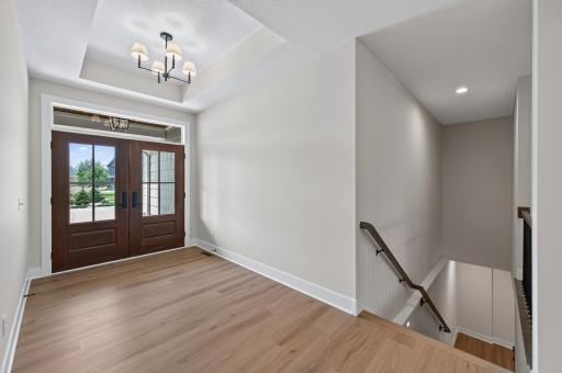 A grand foyer with elegant double doors and a tray ceiling creates a stunning first impression.
